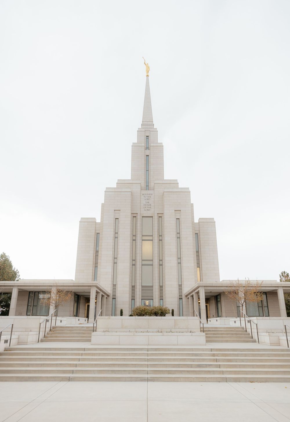 Stunning LDS temple with white spire and golden angel statue against an overcast sky.
