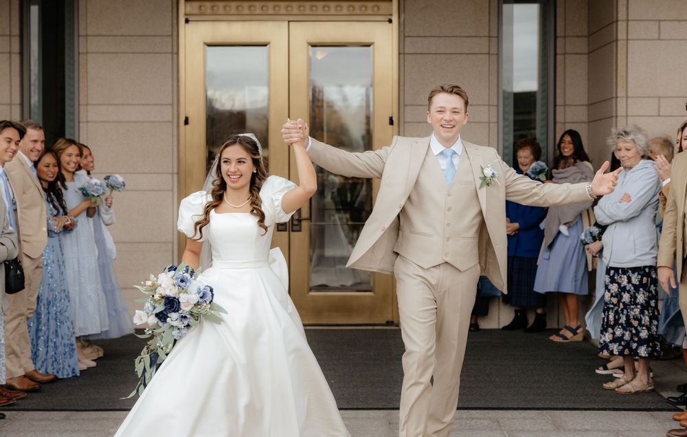 Joyful newlyweds exit LDS temple hand-in-hand as guests celebrate their wedding ceremony.