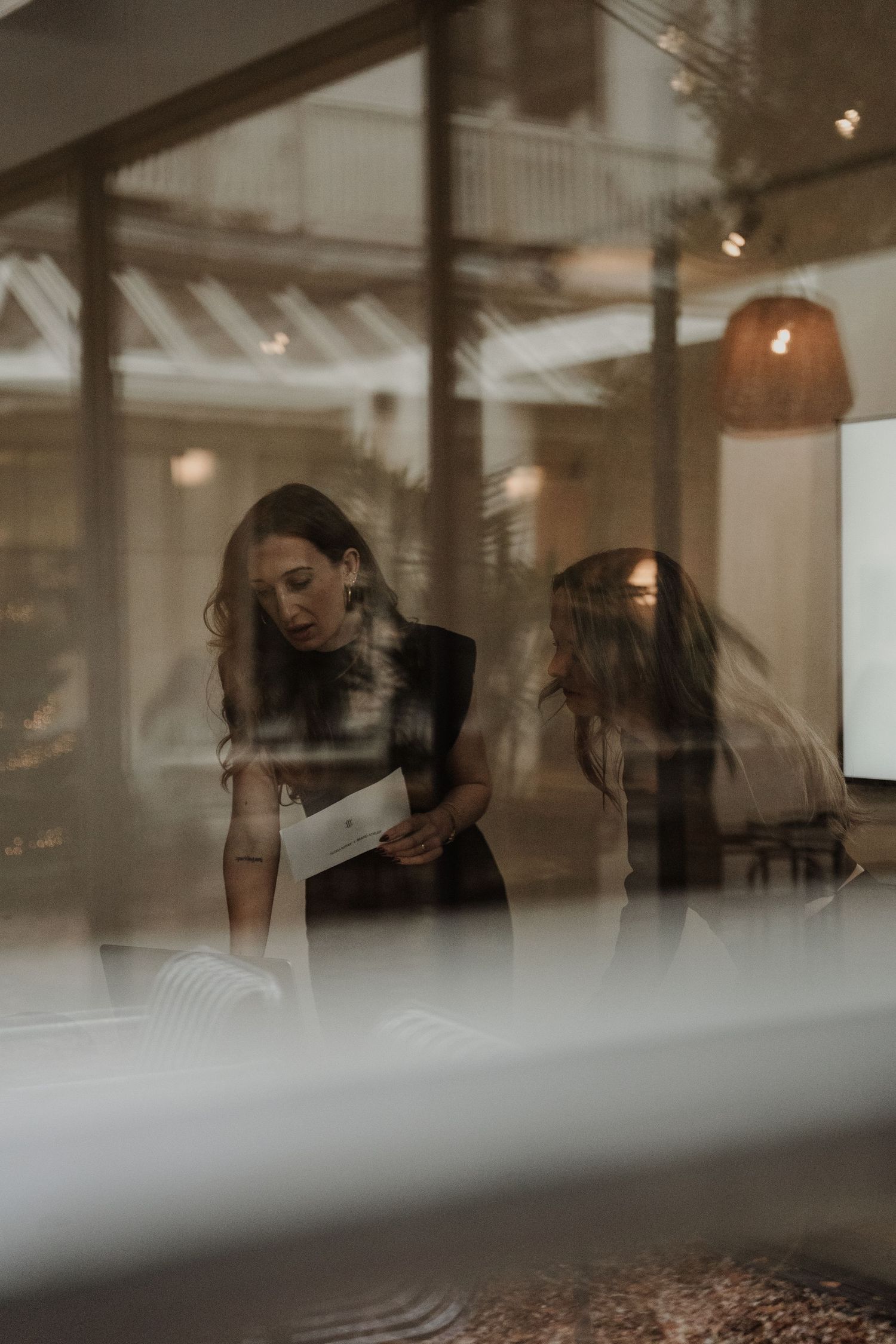 Artistic double exposure photograph of people in an interior space with moody lighting and reflective surfaces.