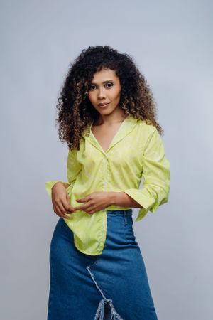 Stylish portrait featuring curly hair model in lime button-down and distressed denim skirt.