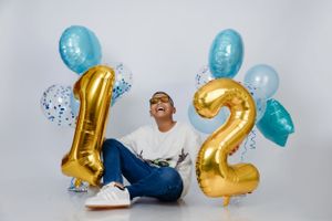 Joyful celebration scene with gold number 12 balloons and blue party decorations.