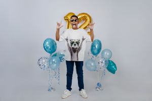 Celebratory pose with gold number 12 balloons and blue party decorations in studio setting.