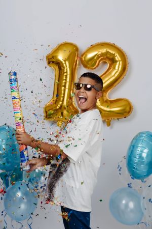 Fun party moment with confetti cannon, gold number 12 balloons and blue decorations.