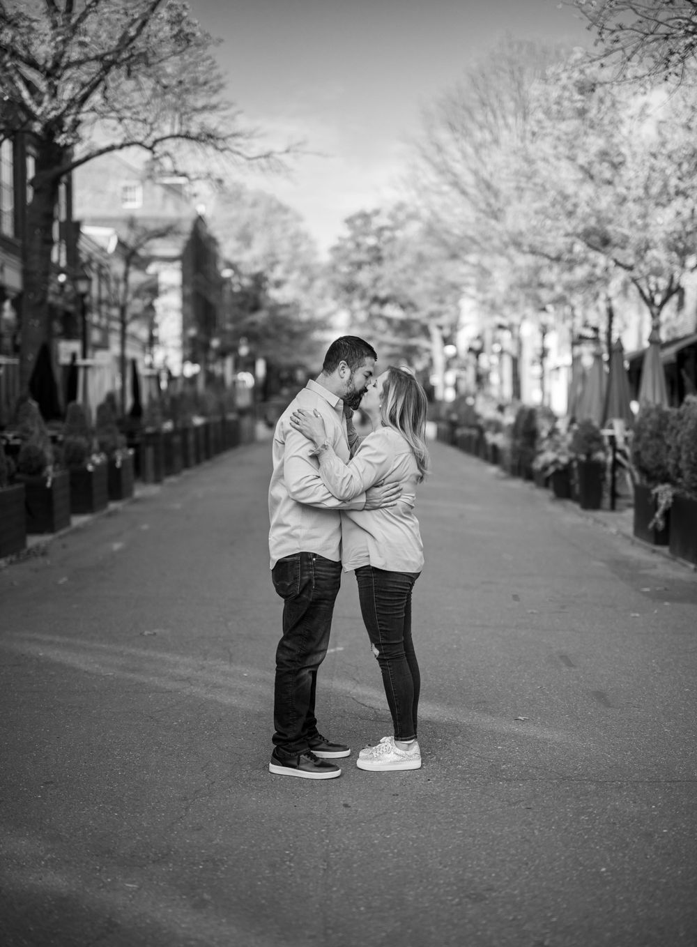 Black and white portrait of a couple embracing in the middle of an empty street.