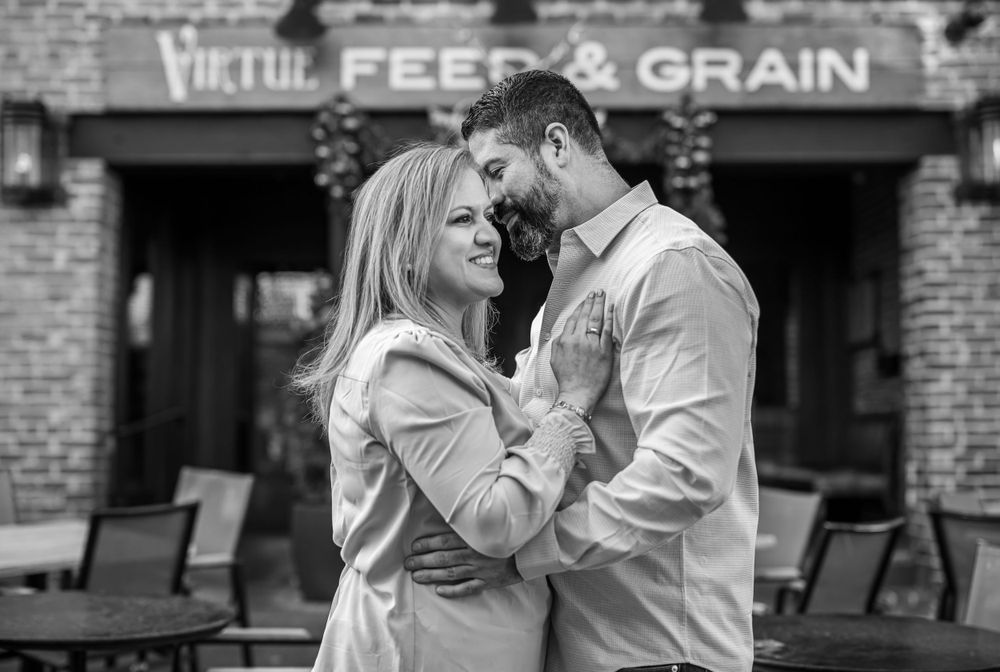 Black and white portrait of a couple embracing outside a vintage Feed & Grain building.
