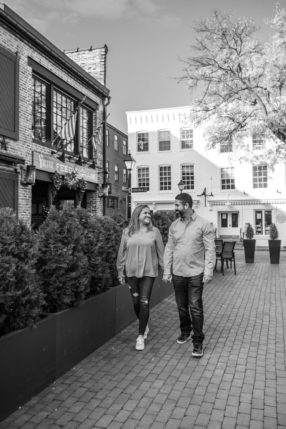 Black and white photo of a couple walking along a historic brick-paved street.