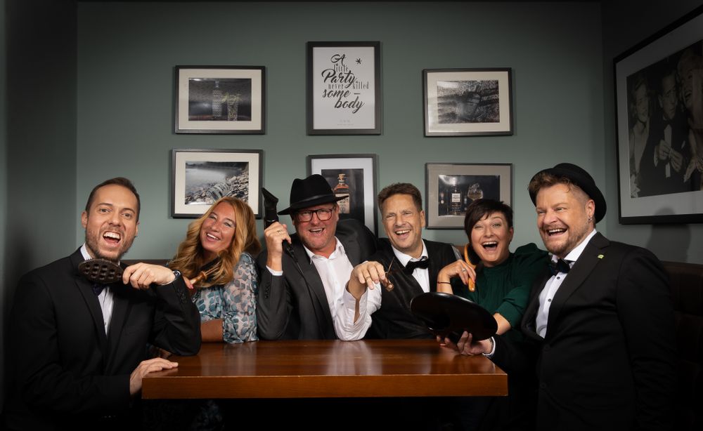 Businessfotografie, Business Project. Group in formal attire posing together at bar in dramatic lighting.