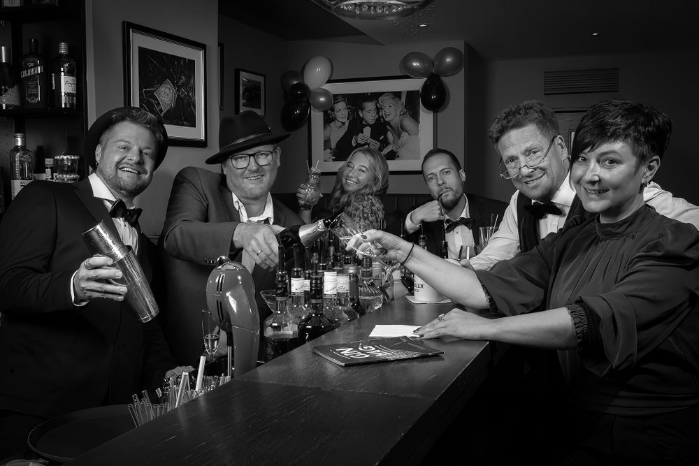 Businessfotografie, Business Project. A group celebrates at a bar with drinks in classic black and white photography.