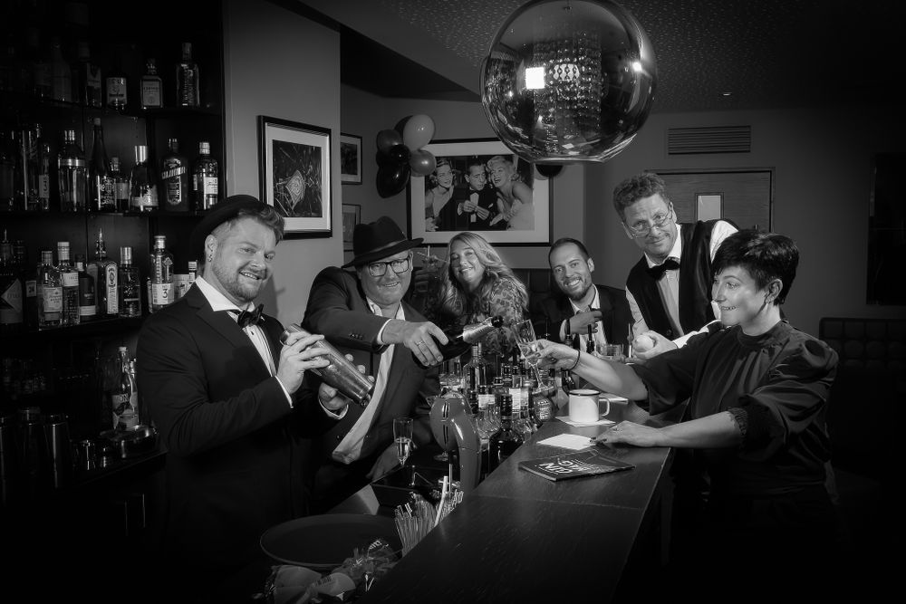 Businessfotografie, Business Projects. Black and white photo of people enjoying drinks at vintage-style bar under disco ball.
