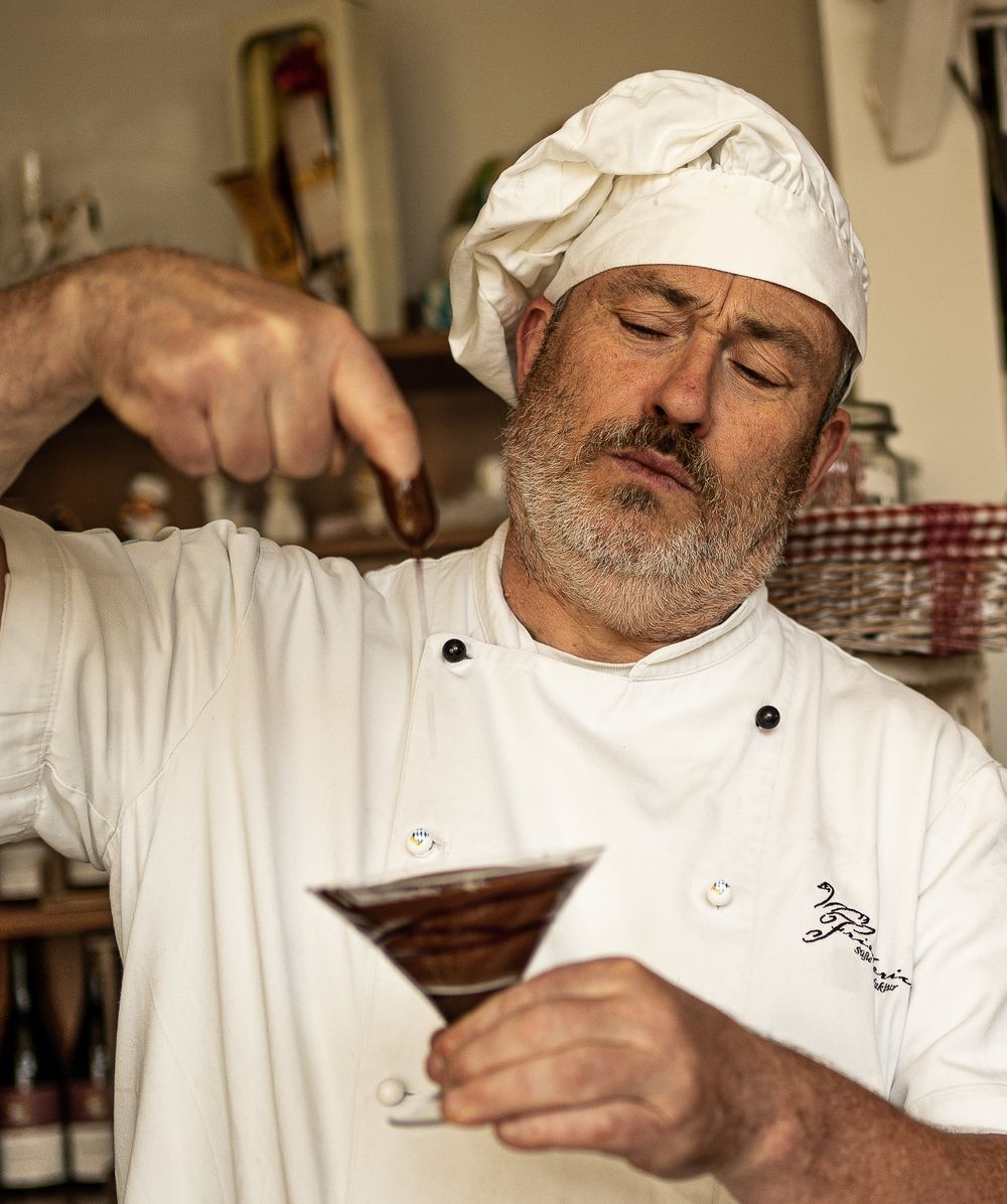 Businessfotografie, Business Projects. Chef in traditional white uniform and hat checks melted chocolate in a glass.