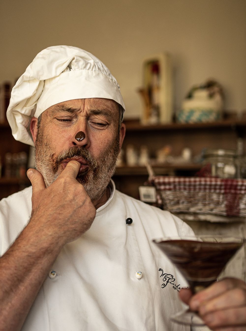 Businessfotografie, Business Projects. Chef in white uniform and hat tastes a chocolate from a glass.