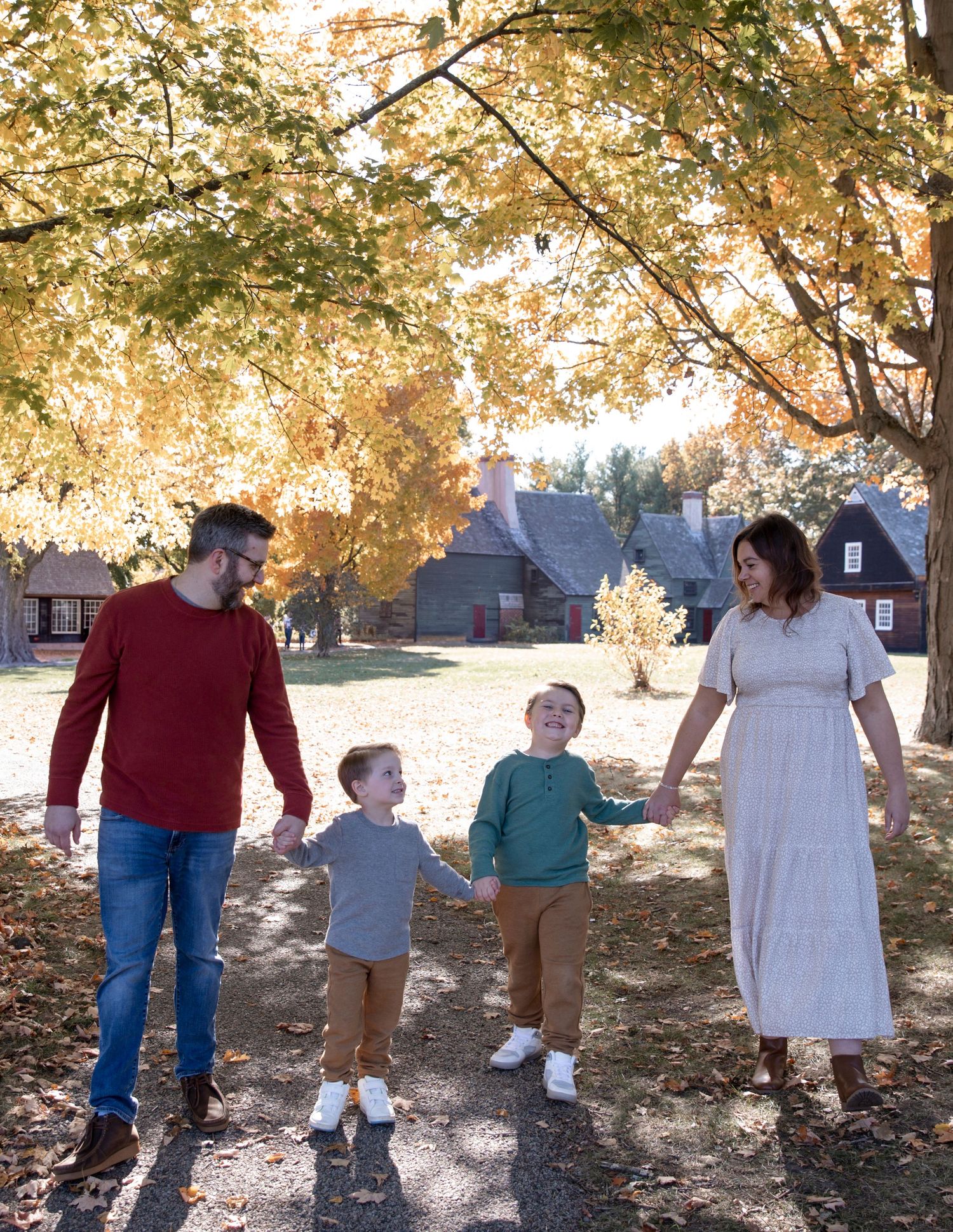 Family walking together under golden autumn trees during a fall photo session.