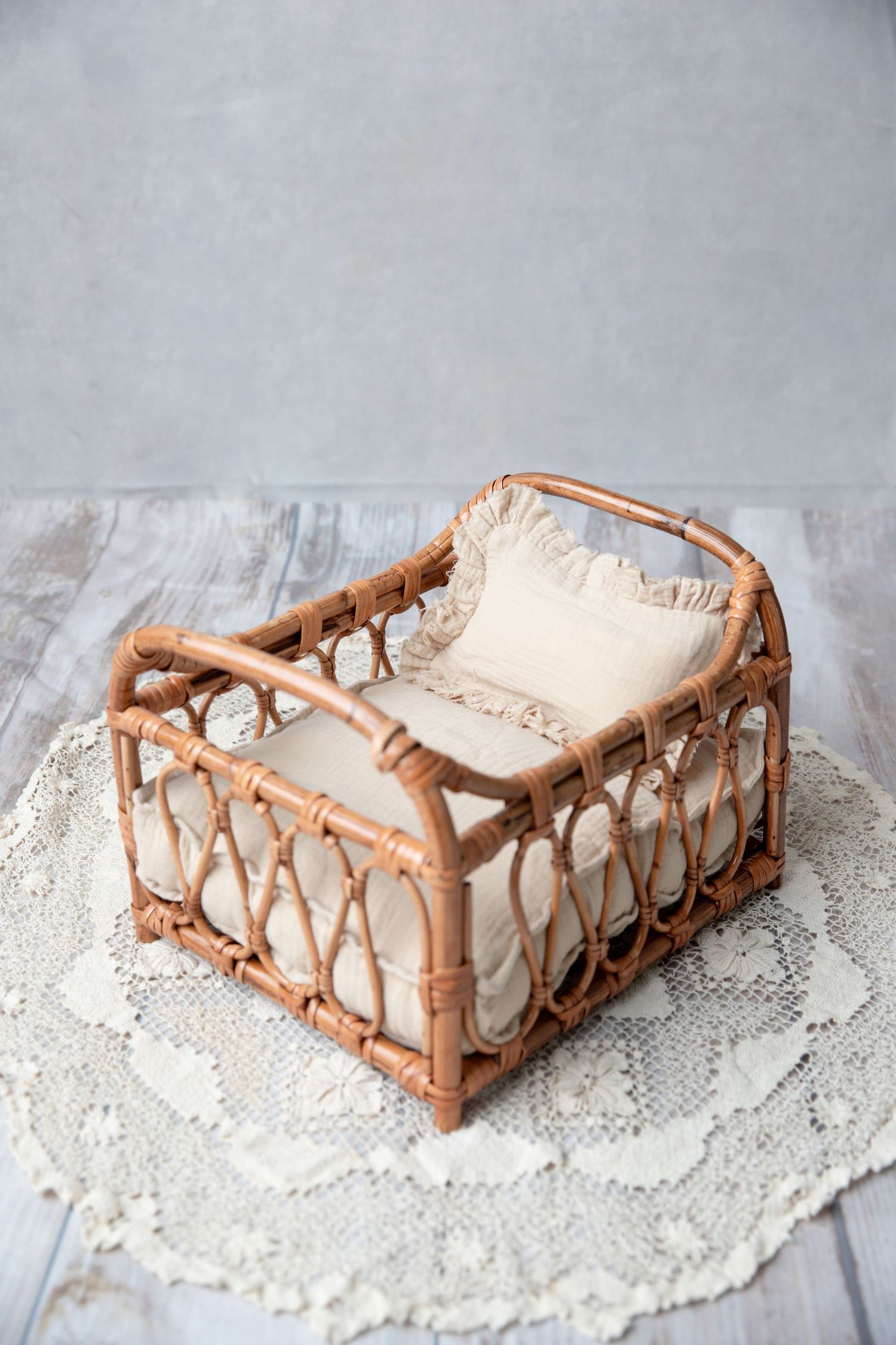 Rustic rattan wicker newborn photography prop basket with cream linen bedding on lace mat.