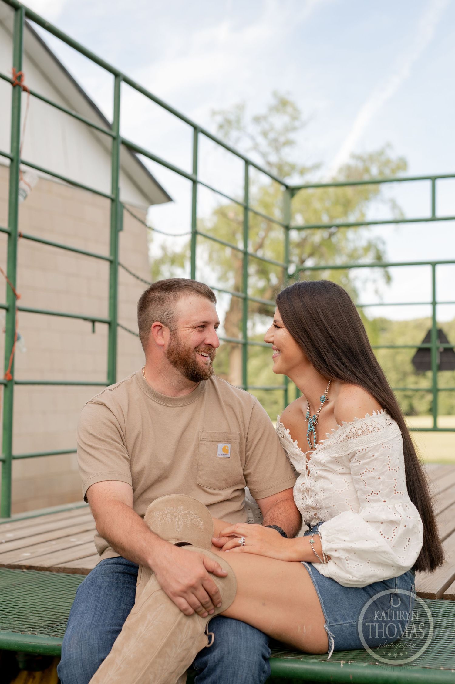 Couple shares laughs while sitting on green bleachers during countryside photoshoot.