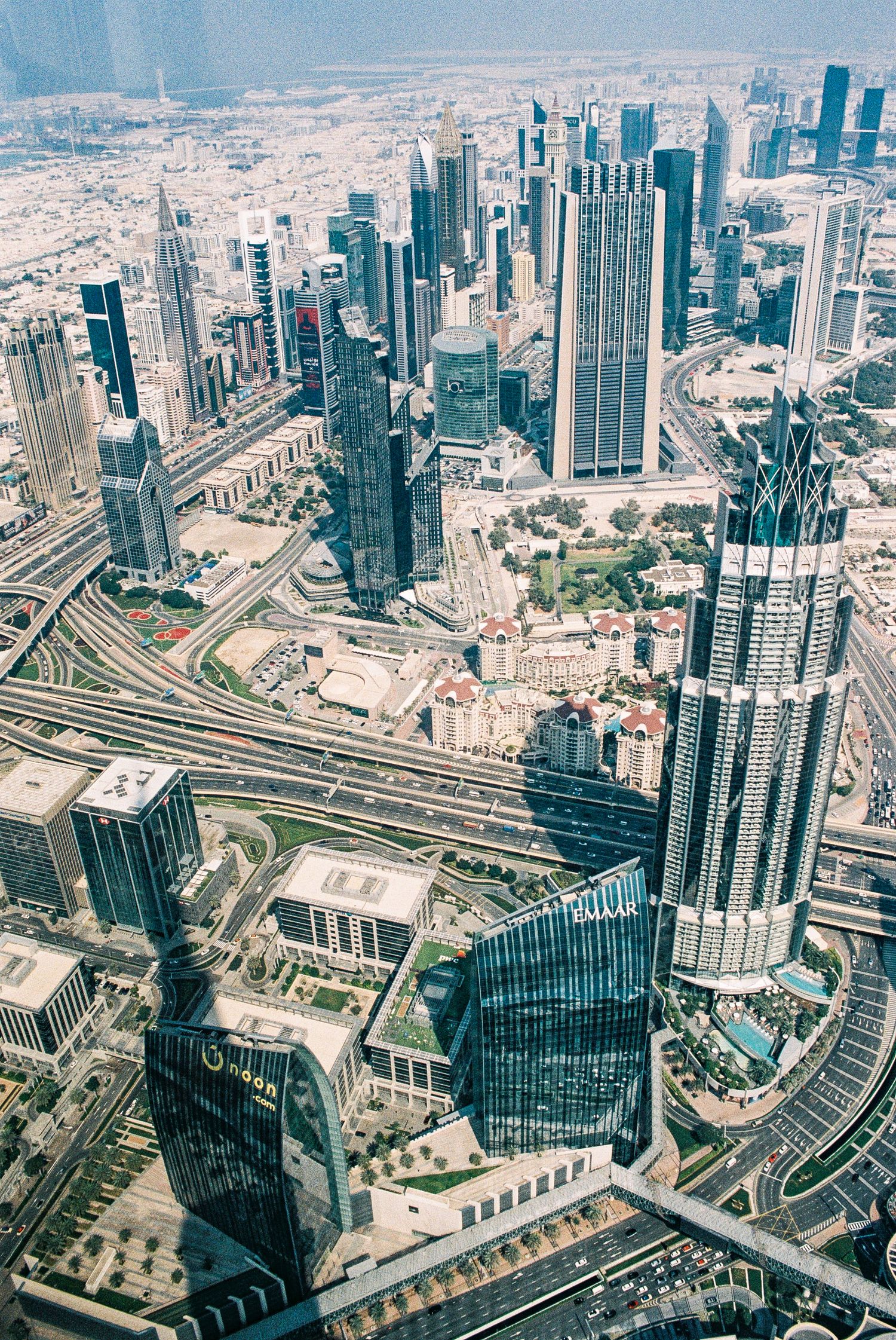 Aerial view of Dubai's modern skyscrapers and highways with the Burj Khalifa dominating the cityscape.