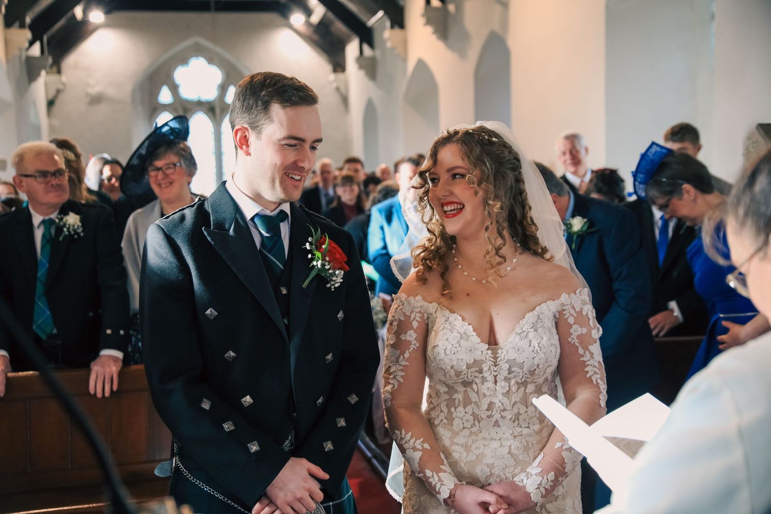 Wedding ceremony moment with couple sharing joyful laughter inside a church.