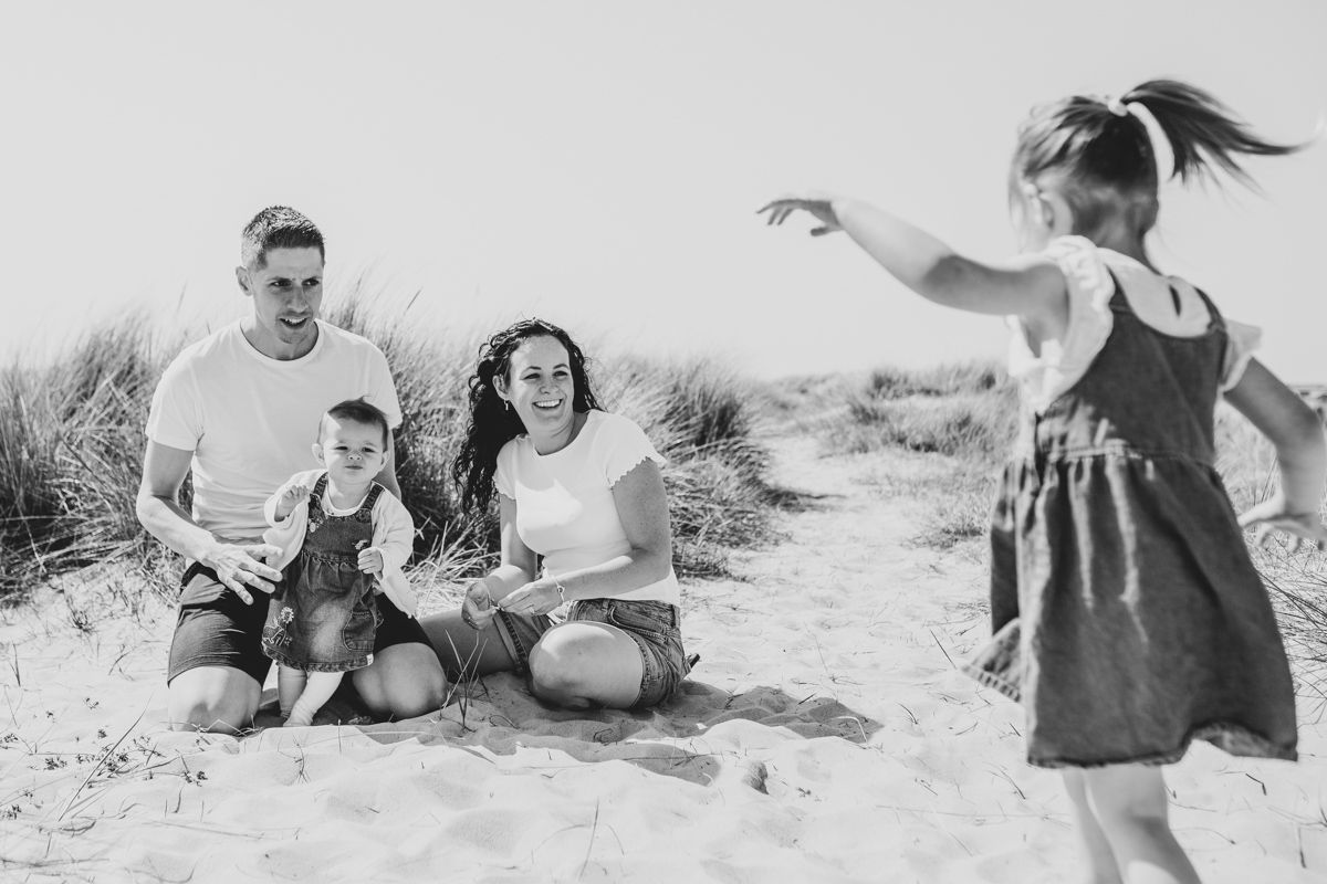 Black and white photo of a family having fun at the beach with sand dunes.