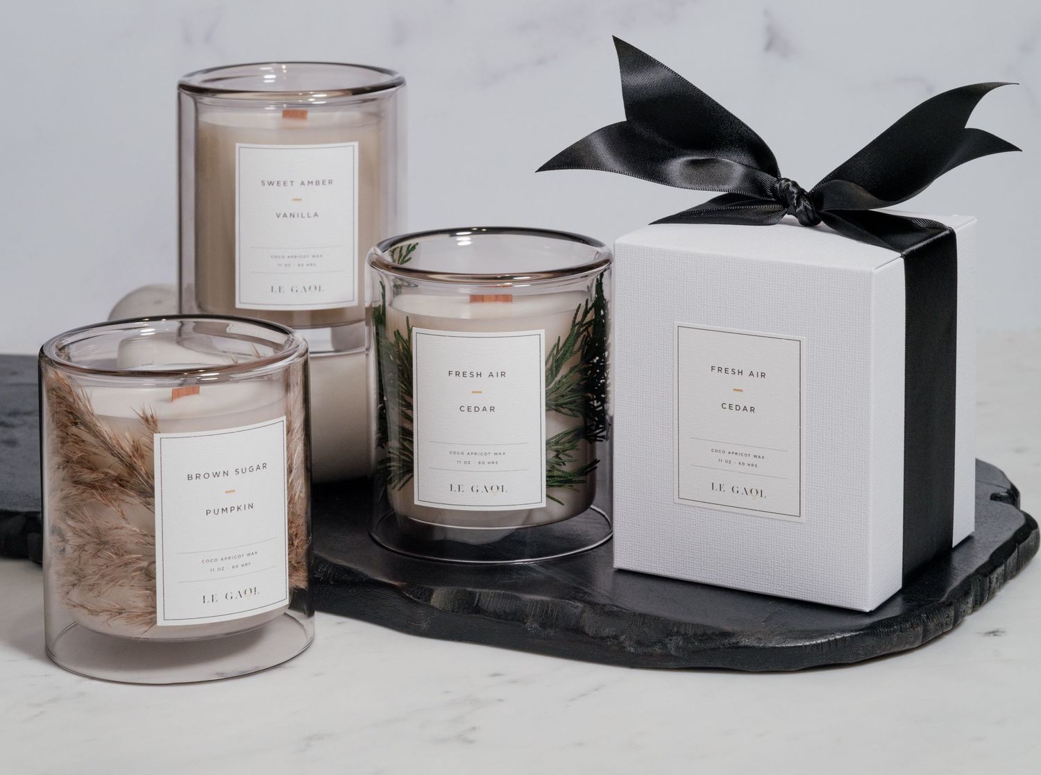 Luxury candle collection with black bow displayed on marble tray.