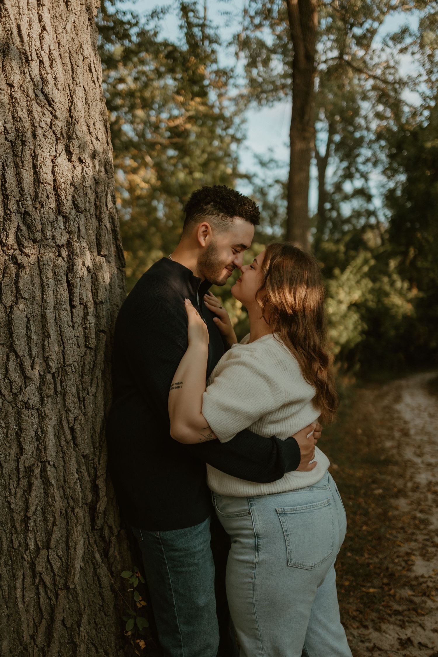 A romantic outdoor scene with a floral dress and beige pants as a couple sits together on a fallen log.