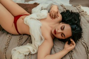 Person in a white lace dress lying on a beige carpet in a romantic boudoir setting.