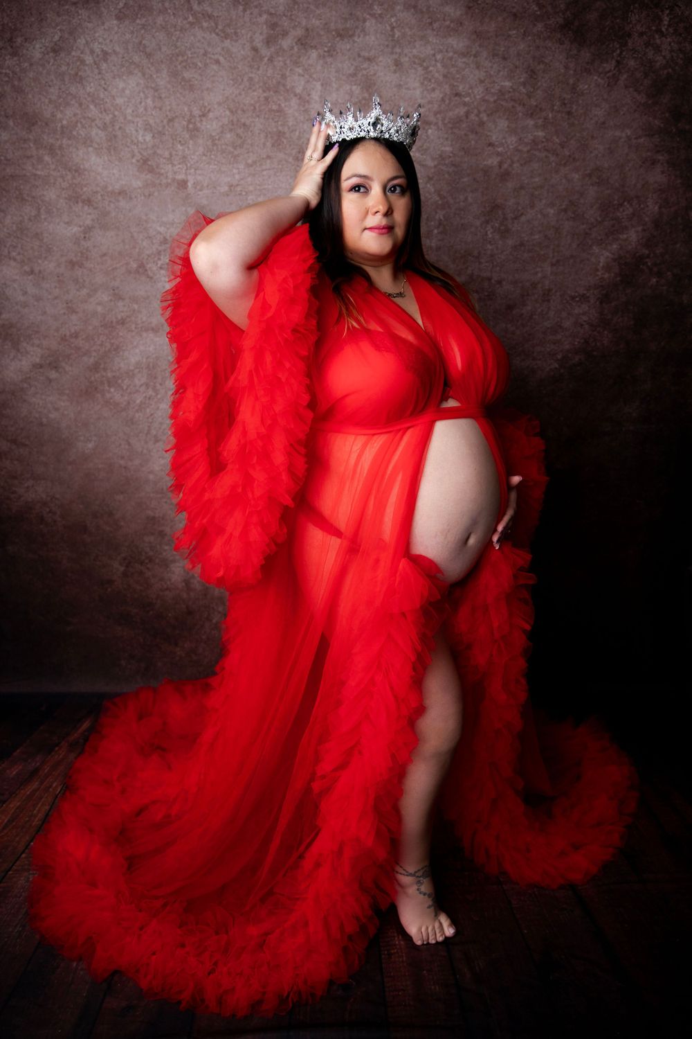 Pregnant woman in red gown and crown during dramatic maternity photography session in Central Florida.