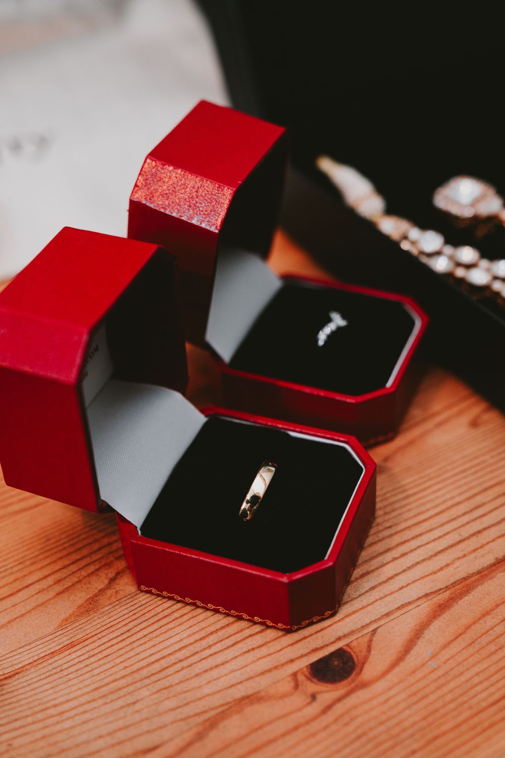 Red jewelry boxes containing wedding rings on a wooden surface.