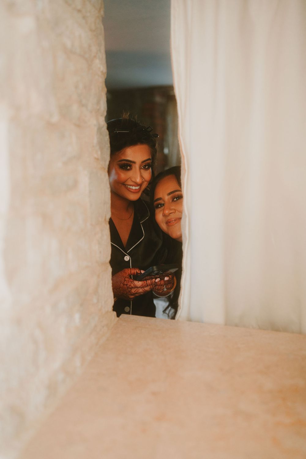 Candid moment of wedding preparation through white curtains.