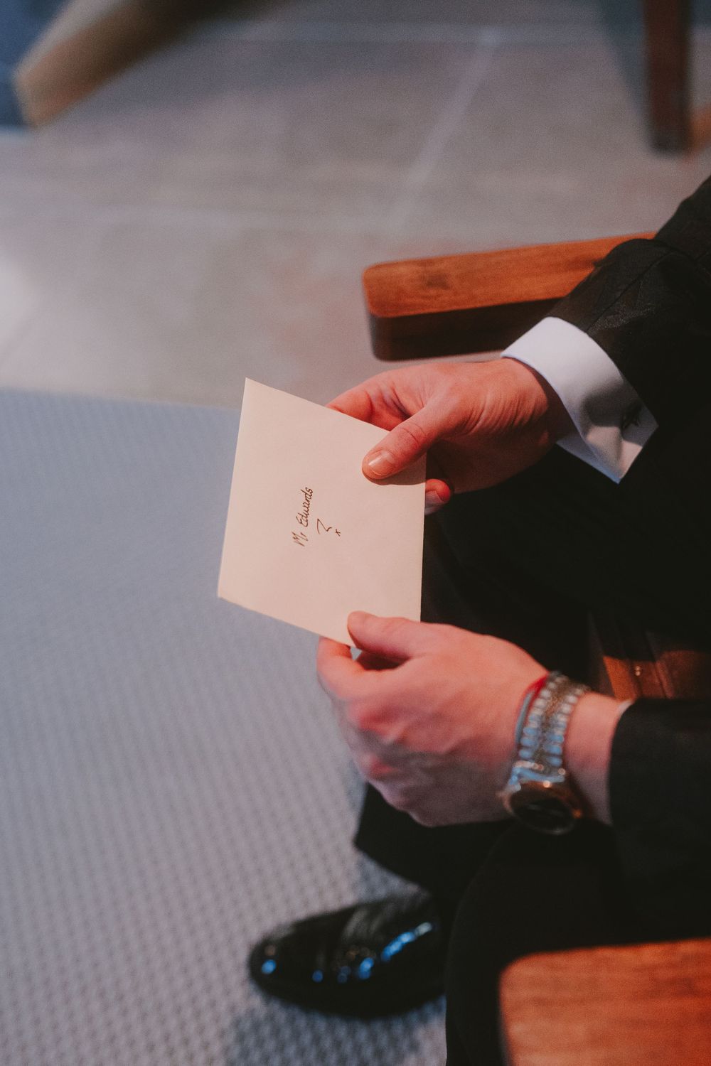 Hands holding a wedding note or card while wearing formal attire.
