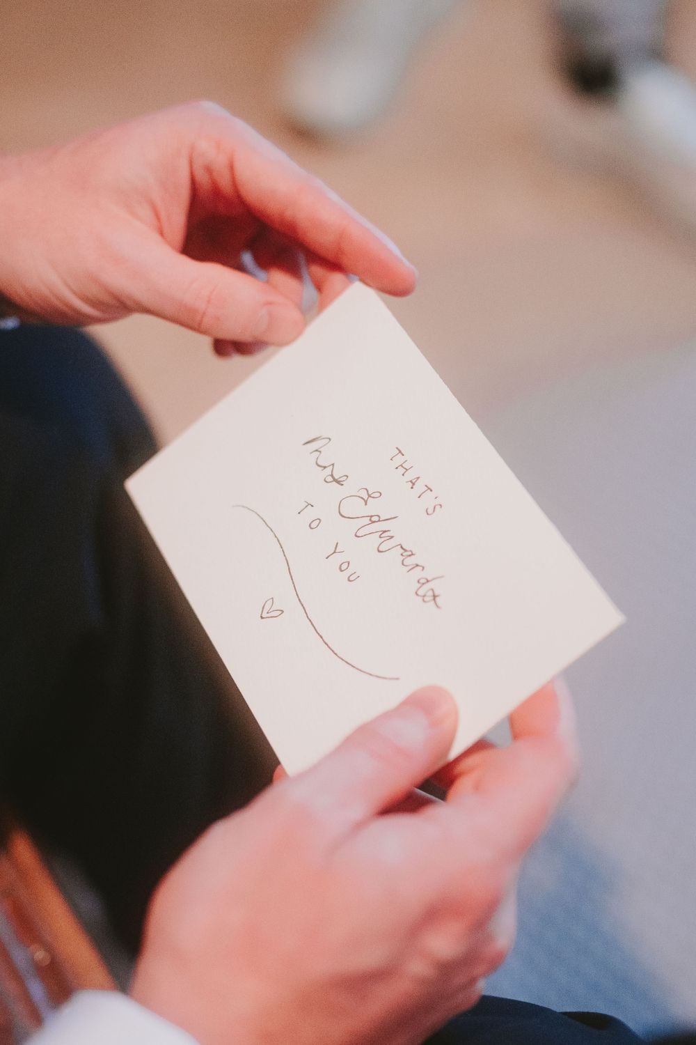 Hands holding a handwritten note with a heart drawn on white paper.