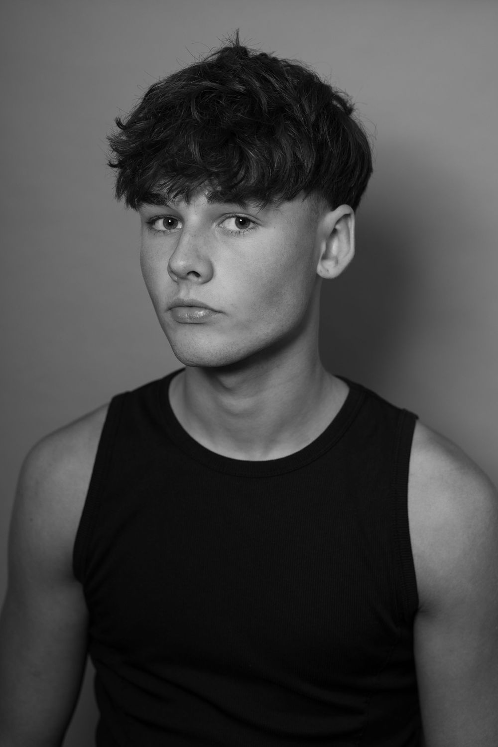 Black and white portrait series showing someone in a sleeveless black shirt against a plain background.