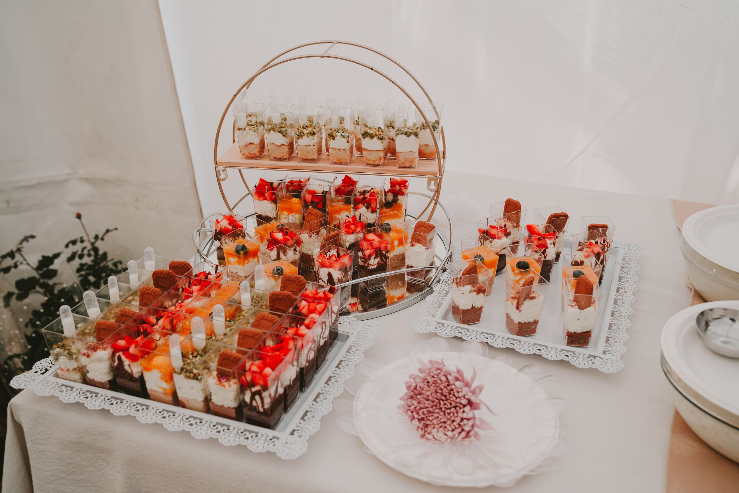 Elegant dessert display with red and gold treats arranged on tiered serving platters.