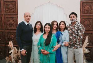 Family group photo against decorative wall backdrop at cultural celebration.