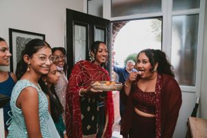Group sharing laughter while holding plates of food during a festive gathering.