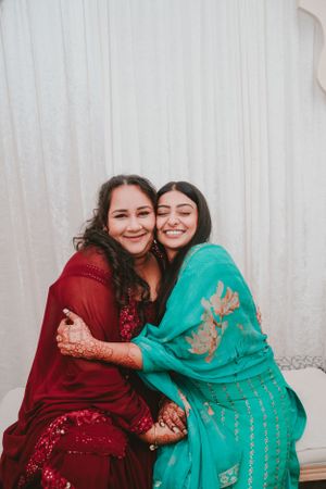Two people in festive attire embracing and smiling against a white backdrop.