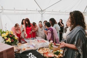 Guests gathered around decorated table with flowers and gifts during cultural celebration.