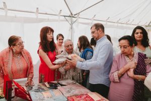 Group gathered around display table with jewelry and gifts during traditional ceremony.