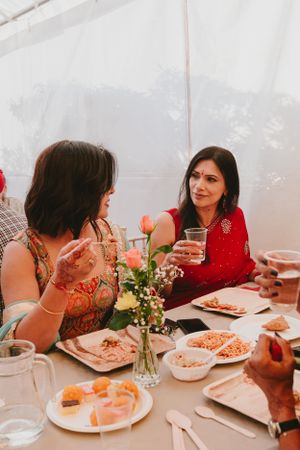 Guests enjoying conversation and food at decorated table during celebration event.