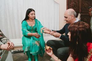 Traditional gift-giving ceremony with guests seated on floor exchanging items during cultural celebration.