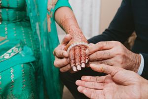 Close-up of hands with intricate henna design during traditional ceremony.