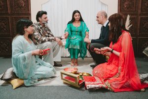 Group gathered on floor in colorful traditional attire during cultural ceremony with decorative items.
