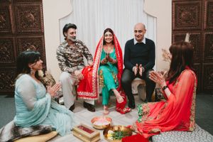 Group gathered on floor sharing traditional South Asian wedding customs and rituals.