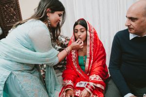 Wedding guests participate in a traditional South Asian ceremony with the bride in red.
