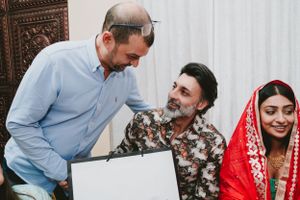 Guests share a light moment while looking at something on a laptop during a wedding celebration.