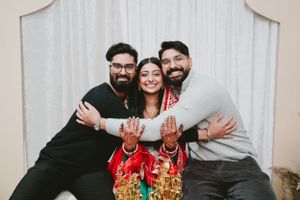 Joyful wedding portrait against white backdrop featuring traditional South Asian ceremonial attire.