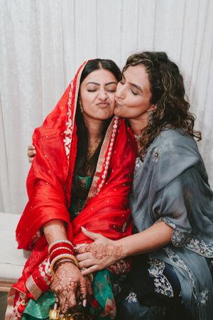 Intimate moment captured during a South Asian wedding ceremony with traditional red and teal attire.