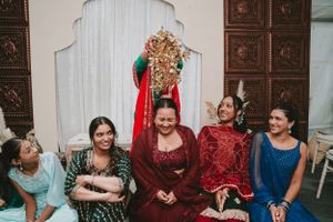 Group photo of wedding guests wearing jewel-toned outfits seated against decorative wall panels.