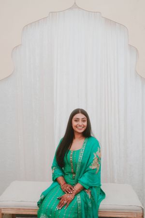 Traditional emerald green Indian outfit showcased in an elegant architectural setting.