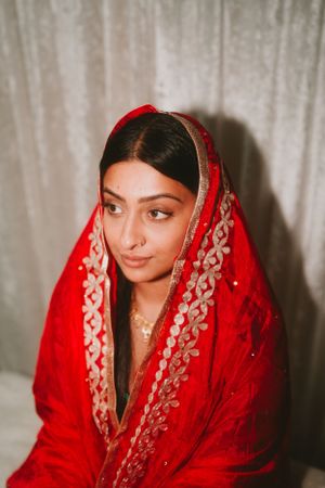 Red and gold embroidered dupatta framing traditional South Asian bridal look.