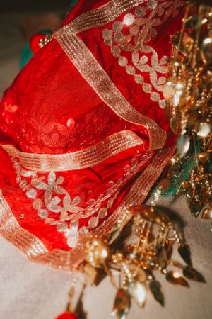 Close-up of a red and gold embroidered bridal sari with intricate lace details and sparkly embellishments.