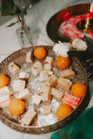 Decorative platter with oranges and sweets arranged on ornate metallic tray for celebration.